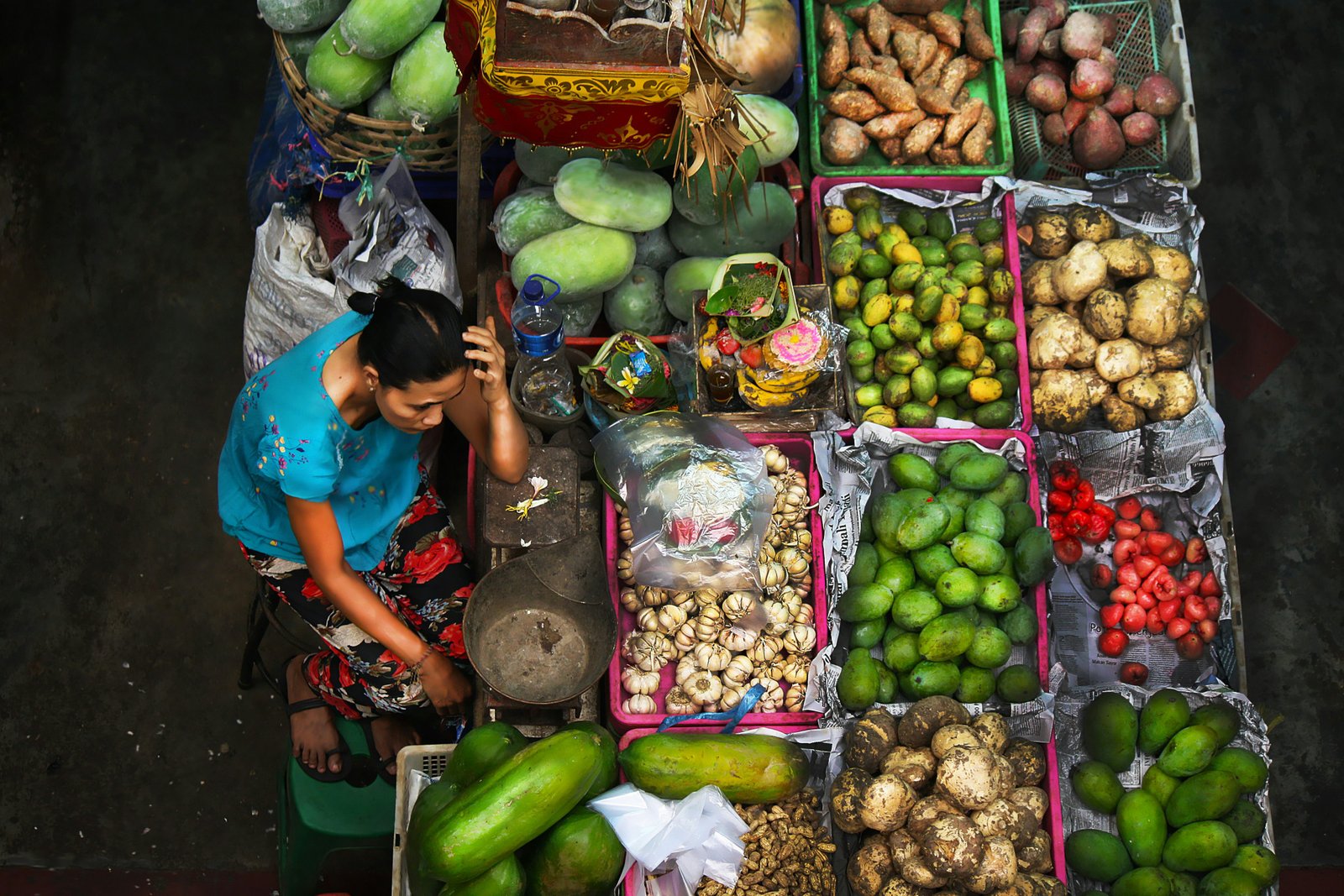Une vue à angle élevé d'une femme vendant des fruits et légumes dans un stand à Pasar Badung Market, Denpasar, Bali, Indonésie