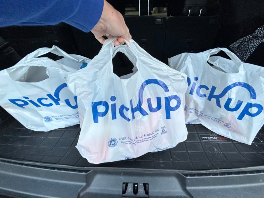 3 sacs Kroger Pickup blancs dans le coffre d'une voiture grise